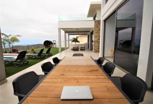 een lange houten tafel met stoelen en een laptop erop bij Villa Jazz in Adeje