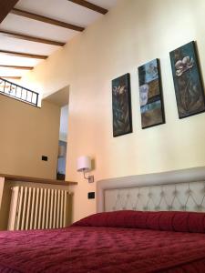 a bedroom with a red bed with pictures on the wall at Hotel Adler in Menaggio