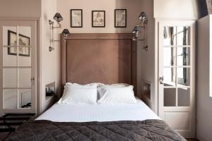 una camera da letto con un grande letto con cuscini bianchi di Hôtel Le Presbytère a Parigi