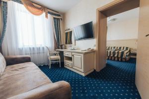 a hotel room with a bed and a desk with a television at Vladimir Hotel in Vladimir