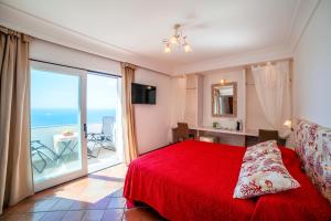 Schlafzimmer mit einem roten Bett und einem großen Fenster in der Unterkunft Villa Anfitrite in Positano