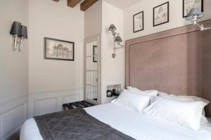 ein Schlafzimmer mit einem großen weißen Bett mit weißen Kissen in der Unterkunft Hôtel Le Presbytère in Paris