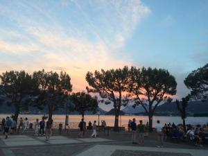 a group of people standing near the water at sunset at Hotel Adler in Menaggio