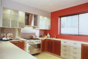 una cucina con pareti rosse e piano cottura forno superiore di Atlantic Waves Guest House a Città del Capo