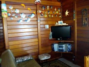 um quarto com uma parede com uma televisão e um sofá em Ilha Comprida-Casa Madeira-Conforto Familiar em Ilha Comprida