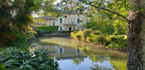 a house and a river in front of a house at Moulin De Ladausse in Monflanquin