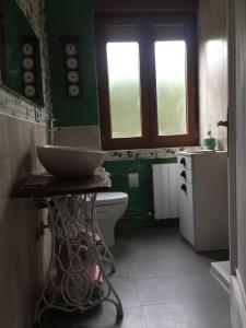 baño verde con lavabo y aseo en El Quinto Pino, en Santibáñez del Val