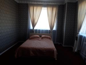 a bedroom with a bed and a window with curtains at Керуен сарайы, гостиница in Aralʼsk