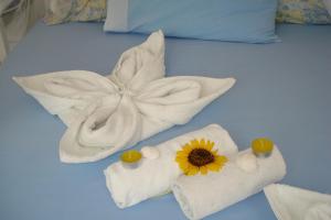 ein Bett mit Handtüchern und einer Sonnenblume darauf in der Unterkunft Paroscarmel studio-apartment in Logaras