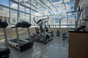 een fitnessruimte met cardio-apparatuur in een kamer met ramen bij Hotel Centro Europeu in Curitiba