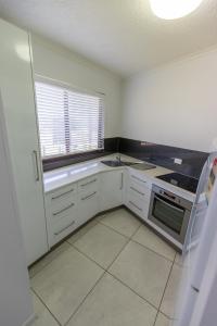 a small kitchen with white cabinets and a window at Rosslyn Bay Resort Yeppoon in Yeppoon