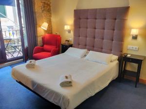 1 dormitorio con 1 cama grande y 1 silla roja en Iturrienea Ostatua, en Bilbao
