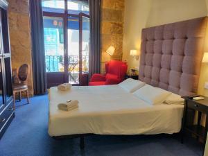 a hotel room with a large bed and a red chair at Iturrienea Ostatua in Bilbao