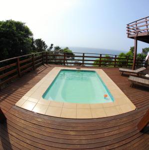 una piscina en una terraza de madera con el océano en el fondo en Golden Beach Village, en Ponta do Ouro