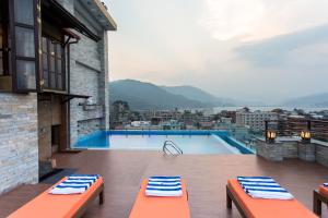 a swimming pool with two benches on a balcony at Hotel Mala Pokhara in Pokhara