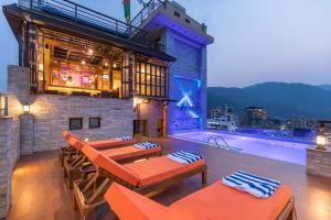 a rooftop patio with tables and chairs and a swimming pool at Hotel Mala Pokhara in Pokhara