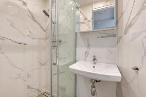 a white bathroom with a sink and a shower at Lion Apartments - Parkowa 33Am2 z parkingiem 2 min od plaży in Sopot
