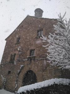 ein Steingebäude im Schnee mit einem Baum in der Unterkunft CASA-ABADÍA DE BANAGUÁS in Banaguás