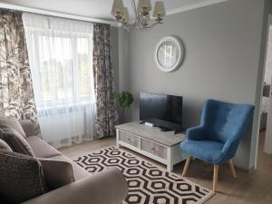 a living room with a tv and a blue chair at Ventspils Seaside Lux Apartments in Ventspils