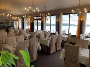 jadalnia z białymi stołami, krzesłami i oknami w obiekcie Hotel Restaurant La Caravelle w mieście Peyrat-le-Château