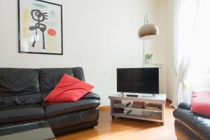 ein Wohnzimmer mit einem schwarzen Ledersofa und einem Flachbild-TV in der Unterkunft Casa Vacanza Fontana Del Delfino in Bergamo