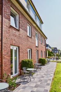 a brick building with tables and chairs in front of it at Hotel Bethanien in Langeoog