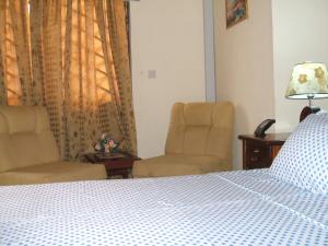 a bedroom with a bed and two chairs and a window at Charis Home Services in Accra