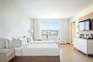 a white bedroom with a large bed and a tv at Melia Sitges in Sitges