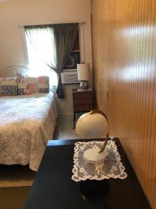 a bedroom with a bed and a table with a lamp at Ohana Pua Hale in Kailua-Kona