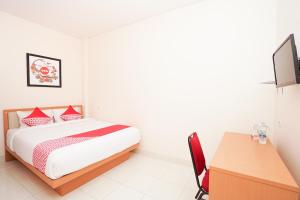 um quarto com uma cama, uma secretária e uma televisão em SUPER OYO 782 Menjangan Residence at Citraland 1 em Lontar