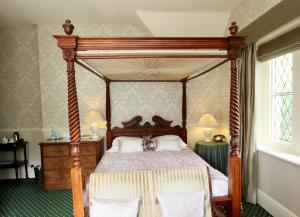1 dormitorio con 1 cama de madera con dosel y 2 sillas en Rylstone Manor en Shanklin