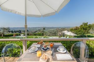 stół z jedzeniem i napojami na balkonie z parasolem w obiekcie Villa I Barronci Resort & Spa w mieście San Casciano in Val di Pesa