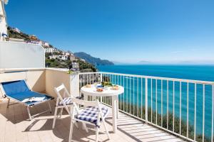 einen Balkon mit einem Tisch, Stühlen und Meerblick in der Unterkunft Edera in Amalfi