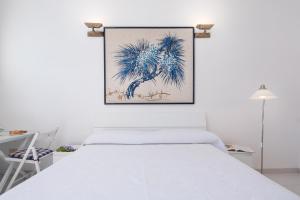 a bedroom with a white bed and a painting on the wall at Edera in Amalfi