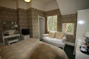 um quarto com uma cama, uma cadeira e uma televisão em Rylstone Manor em Shanklin