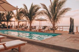 - une piscine dans un complexe avec des palmiers et des chaises dans l'établissement Baja Canoas Hotel, à Canoas de Punta Sal