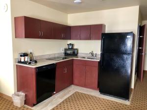 a kitchen with red cabinets and a black refrigerator at Cobblestone Hotel & Suites Pulaski/Green Bay in Pulaski