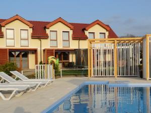 ein Haus mit einem Zaun und einem Pool in der Unterkunft Koralia Domki i Apartamenty Basen z podgrzewaną wodą in Sarbinowo