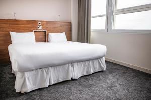 a large white bed in a room with a window at Milton Manchester Hotel in Manchester