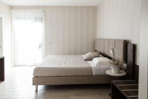 a white bedroom with a large bed and a table at Menta e Rosmarino Rooms in Lazise