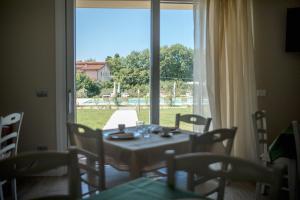 uma sala de jantar com mesa e cadeiras e uma grande janela em Menta e Rosmarino Rooms em Lazise