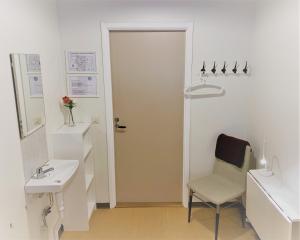 a bathroom with a sink and a chair and a door at Hällefors Vandrarhem-Hostel & Kanotcenter in Hällefors