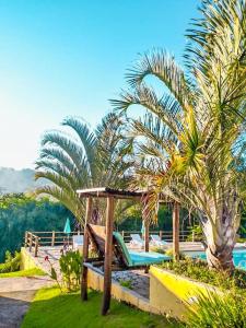 um resort com uma rede de descanso, palmeiras e uma piscina em Fazenda Paisagem Chalés em Serra Negra