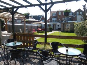 eine Terrasse mit Tischen und Stühlen unter einer Pergola in der Unterkunft B&B De Passant in Breskens