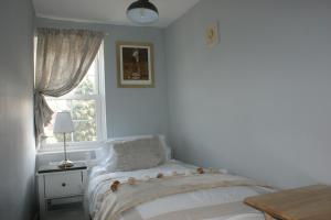 a white bedroom with a bed and a window at Wayside Cottage in Saint Osyth
