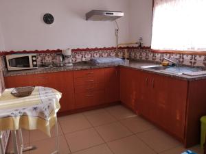 a kitchen with wooden cabinets and a sink and a microwave at Prothea Home in Vila Chã