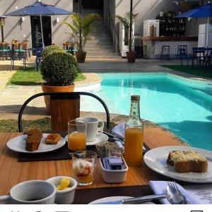 - une table avec de la nourriture et des boissons à côté de la piscine dans l'établissement Casa Rosa Hotel Boutique, à Petrópolis