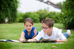 zwei Kinder, die auf dem Gras liegen und Bücher lesen in der Unterkunft Holiday Home Jonckershof in Middelkerke