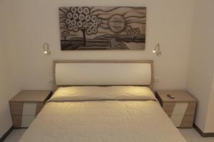 a bedroom with a bed with two tables and a painting at Casa Vacanze Mirabile in Marsala