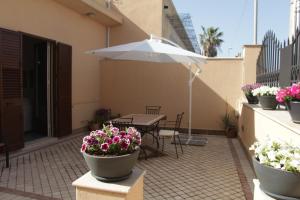 a patio with a table and flowers and an umbrella at Casa Vacanze Mirabile in Marsala